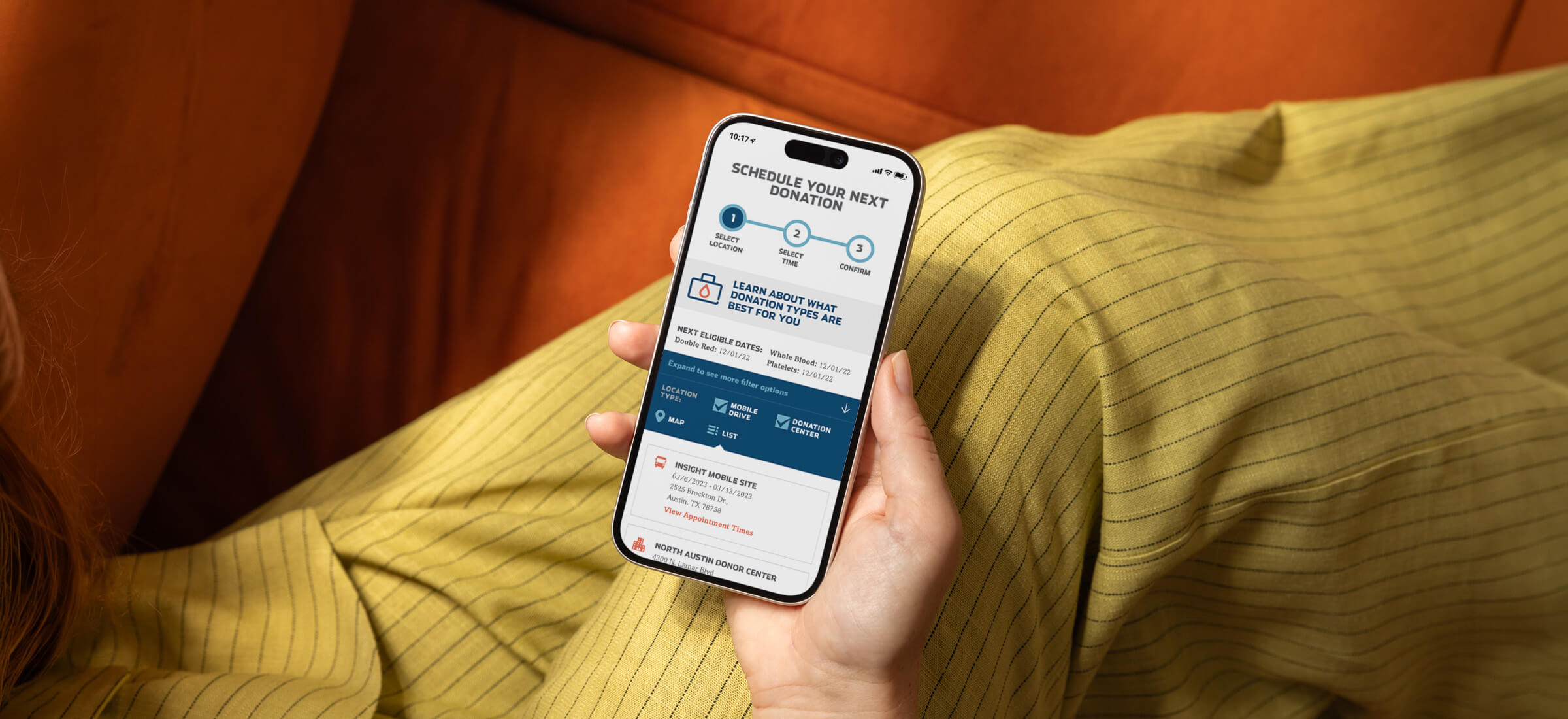 Someone sitting on their couch looking at the We Are Blood donor portal on their phone